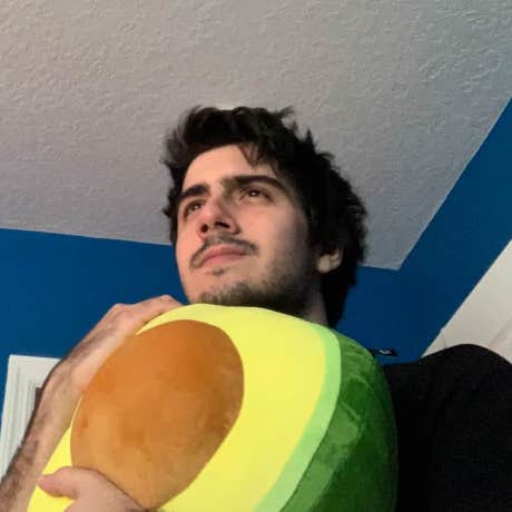 Photo of Carlos Chacin, looking away while clutching an avocado Plushie