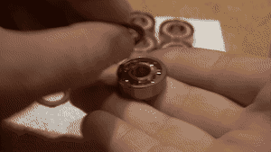 A GIF of 2 hands applying a bearing shield to the exposed side of a bearing by pressing it on